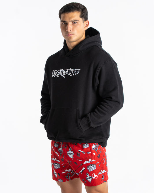 Person wearing a black hoodie with a logo and red shorts with a pattern.
