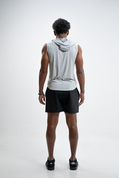 Person wearing a sleeveless gray hoodie and black shorts on a white background